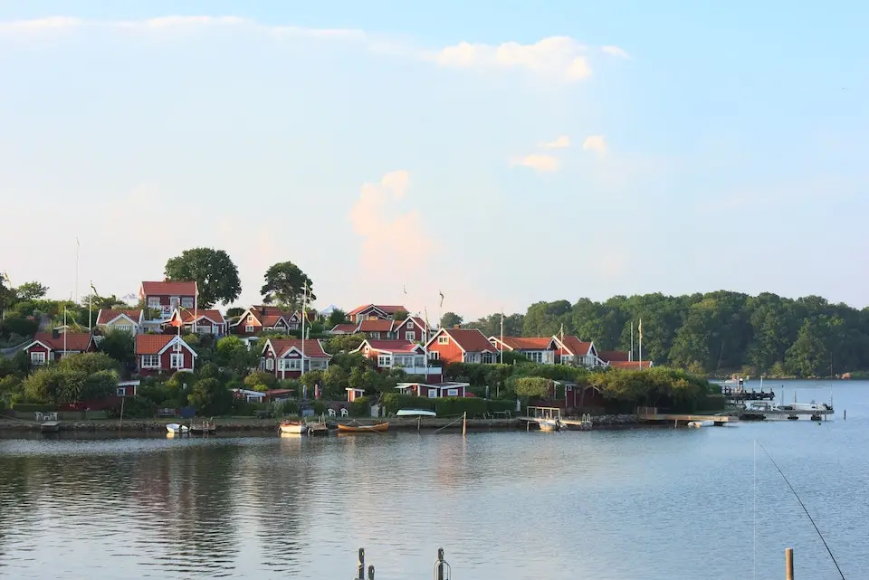 Kustby med röda stugor och båtar vid vattnet i Blekinge län