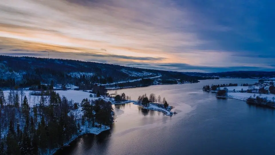 Flygbild över ett snötäckt landskap med älv i solnedgång, Västernorrlands län